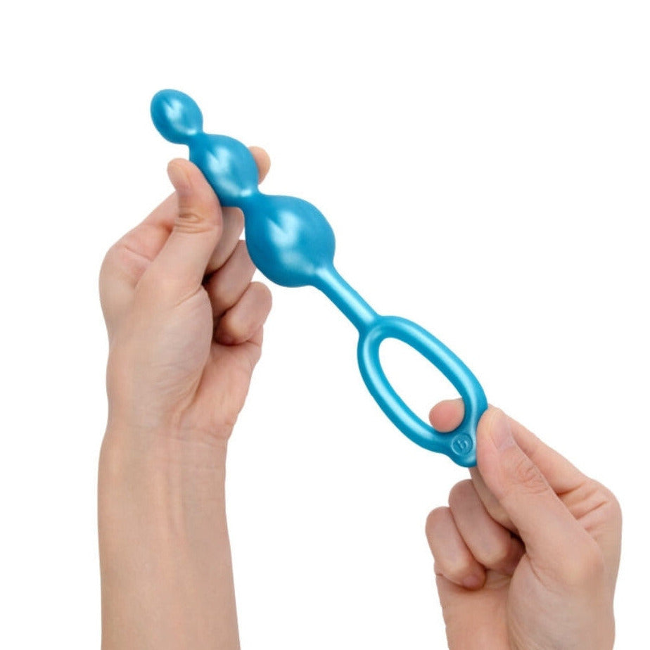 Blue anal toy held by hands on a white background
