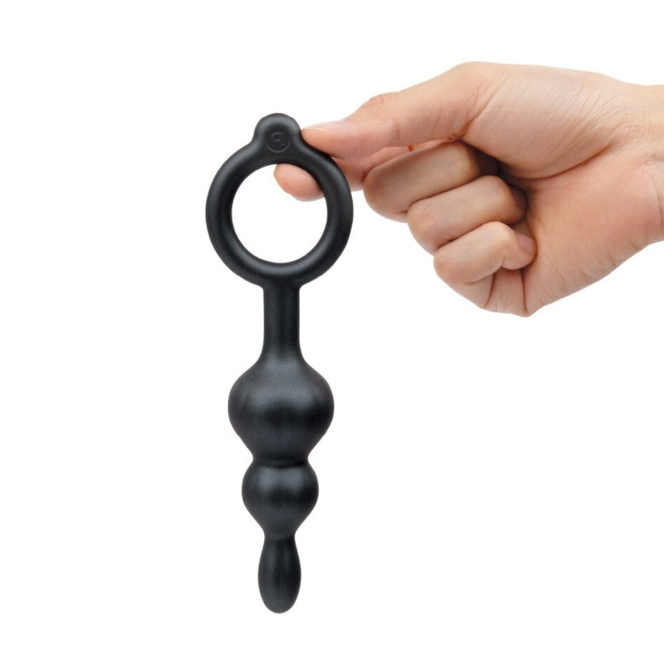 Black handheld anal massager held by a hand on a white background