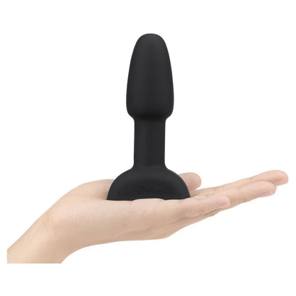 Black silicone butt plug held in a hand on a white background
