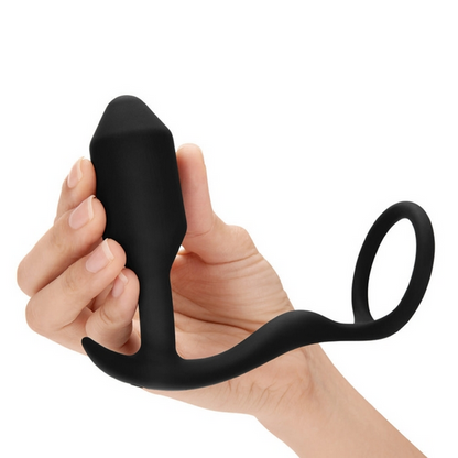 Black silicone anal plug cock ring held in a hand on a white background