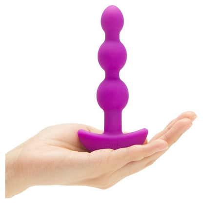 Purple silicone butt plug held in a hand on a white background