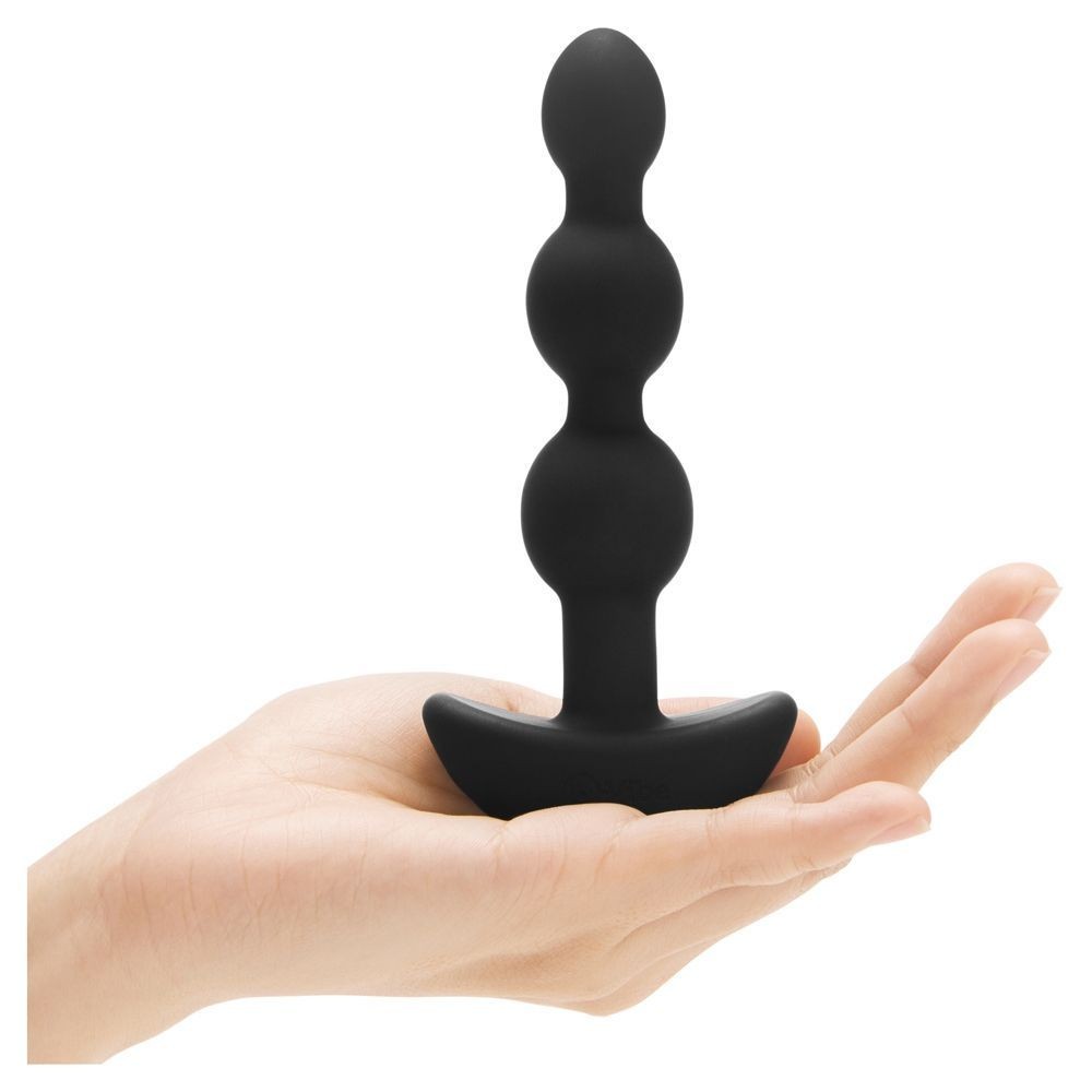 Black silicone butt plug held in a hand on a white background