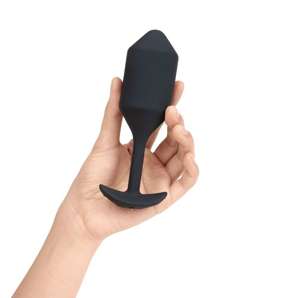 Black silicone product held in a hand against a white background