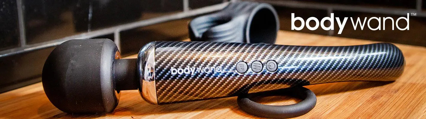 Carbon fiber texture handheld device with 'bodywand' branding on a wooden surface.